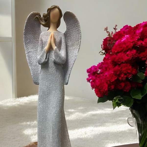 Angel figurine beside a vase of bright pink flowers