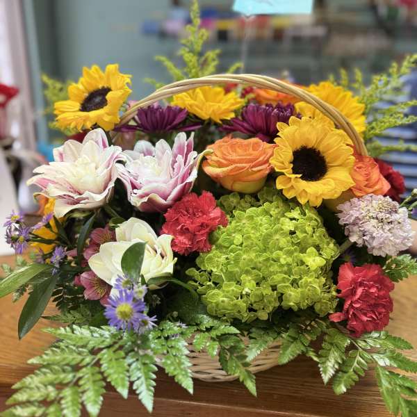 Basket arrangement with sunflowers, roses, hydrangea, and carnations