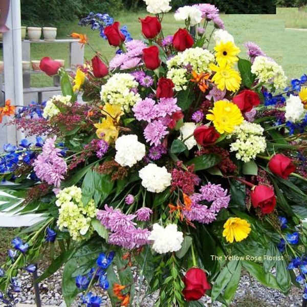 Large mixed floral spray with red roses, yellow daisies, and purple blooms