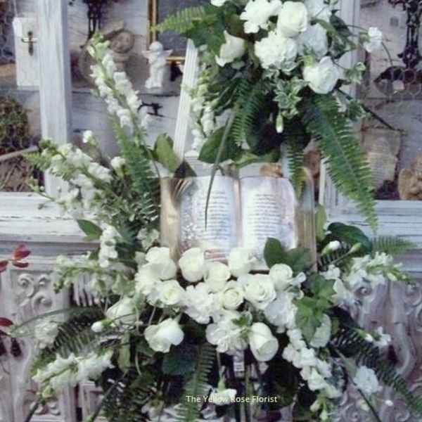 White floral funeral spray on an easel with roses and lilies