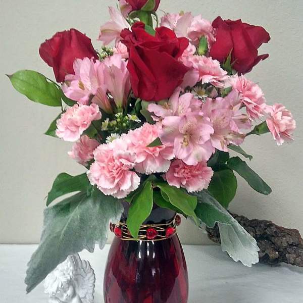 Red roses and pink flowers arranged in a burgundy vase
