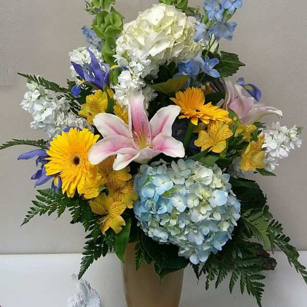 Mixed bouquet in a tall vase with lilies, hydrangeas, and daisies