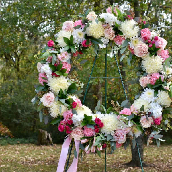 Large floral wreath with pink and white flowers on a metal stand