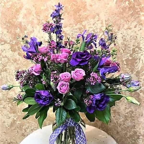 Pink and purple bouquet in a glass vase with a ribbon