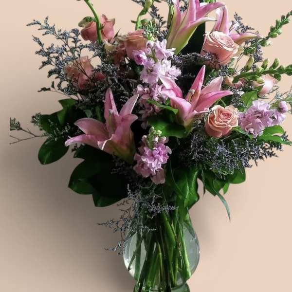 Pink lilies and roses in a clear glass vase