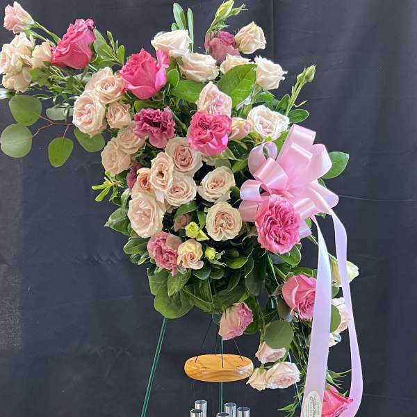 Pink and blush rose arrangement on a stand with a ribbon bow