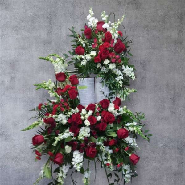 Standing floral spray with red roses and white flowers on an easel