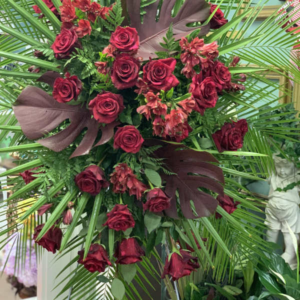 Large arrangement of red roses with tropical leaves and palm fronds