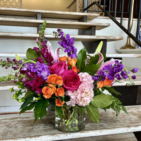 Mixed bouquet of pink, orange, and purple flowers in a glass vase