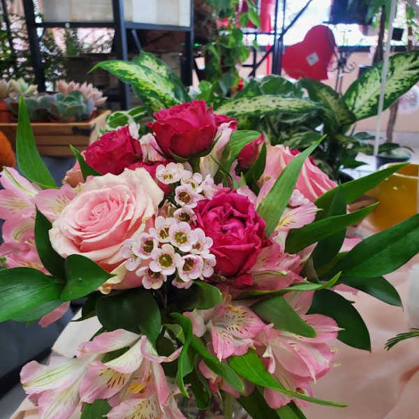 Pink and red roses with pink alstroemeria in a clear glass vase.