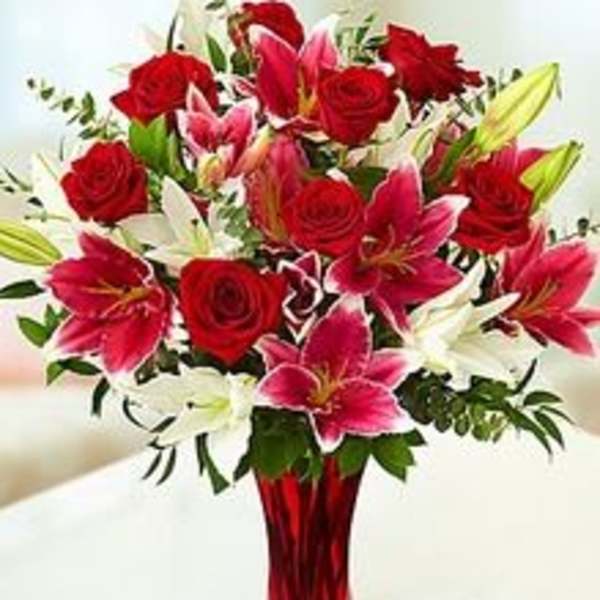 Bouquet of red roses and pink lilies in a red glass vase