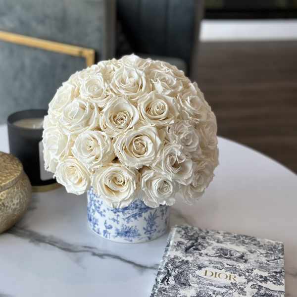 Round bouquet of white roses in a blue-and-white patterned container