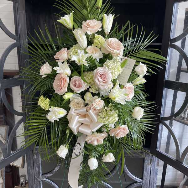 Standing spray of pale pink roses and white lilies with palm fronds