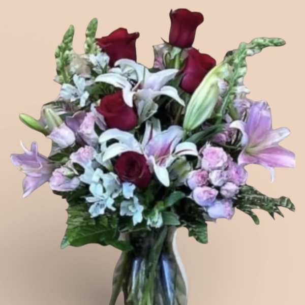 Bouquet of red roses, white lilies, and lavender flowers in a glass vase