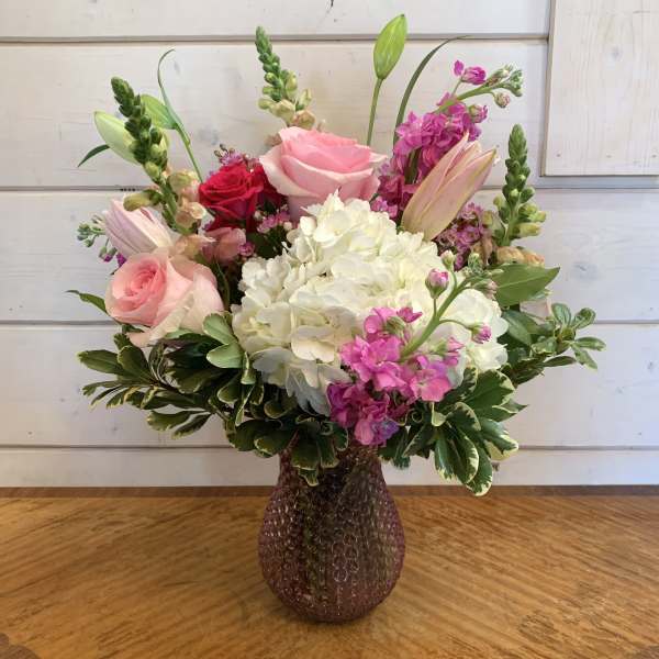 Pink and white floral arrangement in a textured glass vase