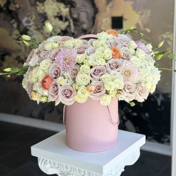 Pastel roses and dahlias arranged in a pink hat box
