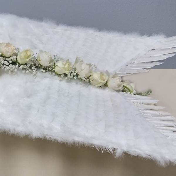 White rose floral arrangement with large white feather wings