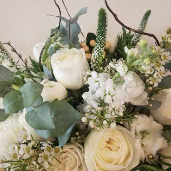 White rose arrangement with round blooms, filler flowers, and eucalyptus accents