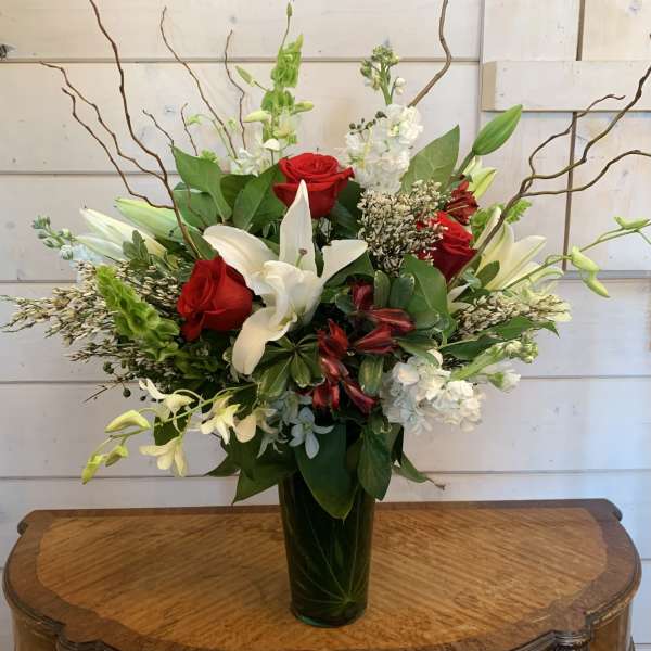 Red roses and white lilies arranged in a tall glass vase