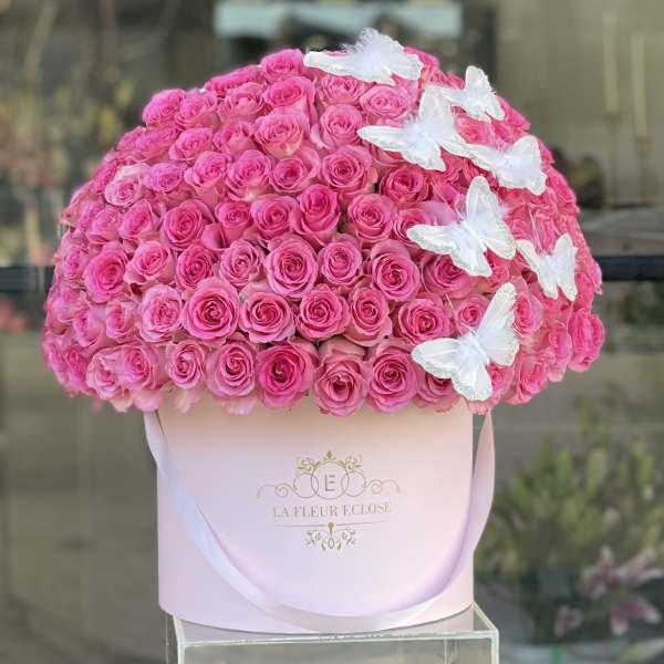 Large pink rose arrangement in a pale pink box with white butterfly accents