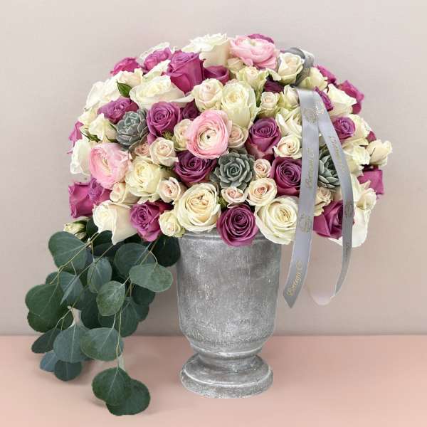 Pink, white, and purple rose bouquet in a silver vase with ribbon