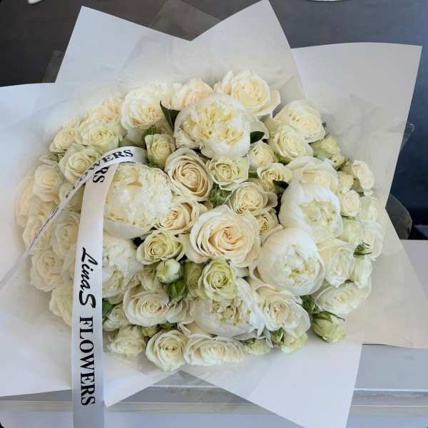 Bouquet of white roses and peonies wrapped in white paper