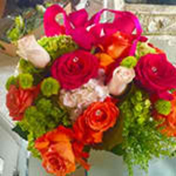Vibrant bouquet of hot pink, orange, and green flowers with a pink ribbon handle