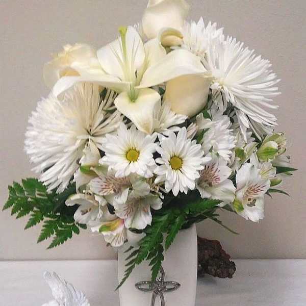 White floral arrangement in a tall vase with an angel figurine