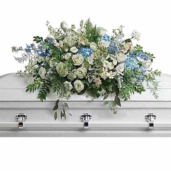 White and blue floral casket spray on a white casket