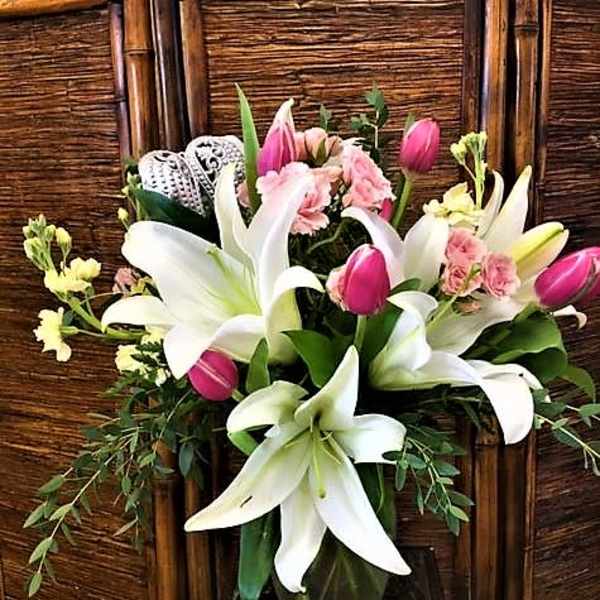 Bouquet of white lilies and pink tulips in a glass vase