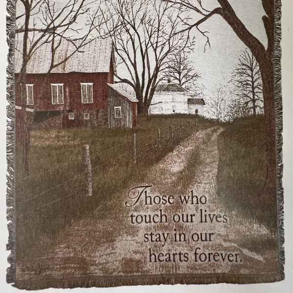 A woven memorial blanket showing a farmhouse scene with a sympathy message.