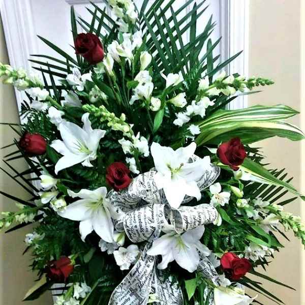 Standing sympathy spray with white lilies and red roses on a ribboned easel