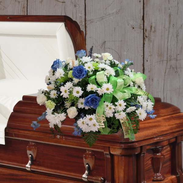 White and blue floral spray on a wooden casket