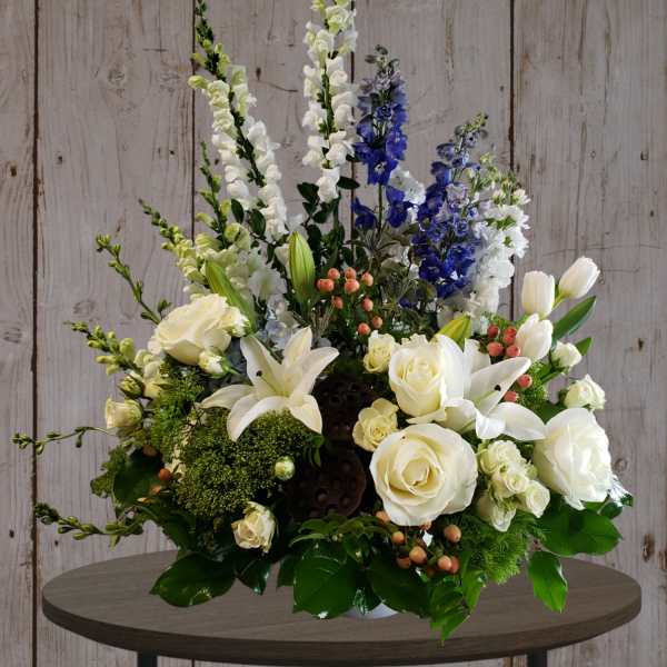 White roses and lilies with blue delphinium in a low arrangement