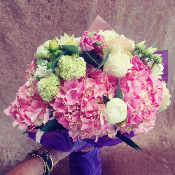 Pink and white bouquet with hydrangeas and roses wrapped in purple paper
