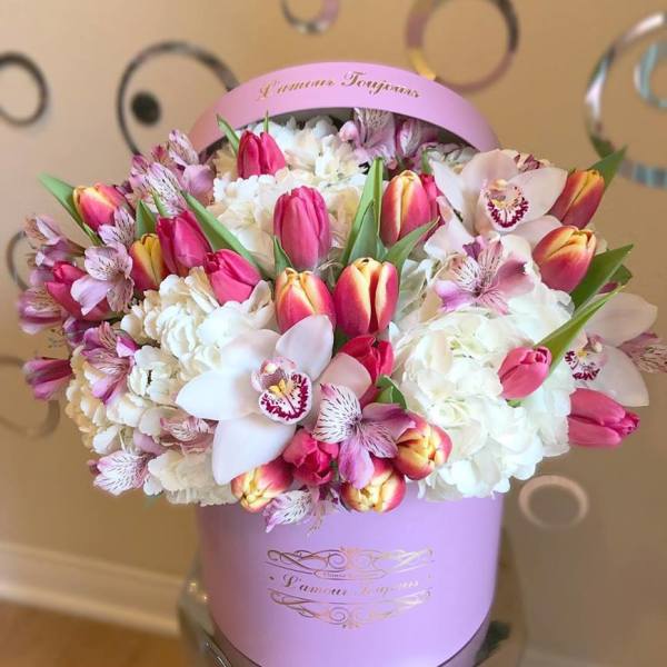 Round pink hat box of tulips, orchids, hydrangeas, and alstroemeria in white and pink tones