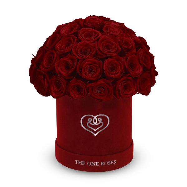 Red roses arranged in a round velvet box with a heart emblem