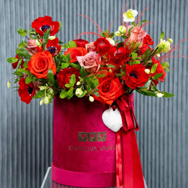 Red and pink floral arrangement in a magenta hatbox with ribbon