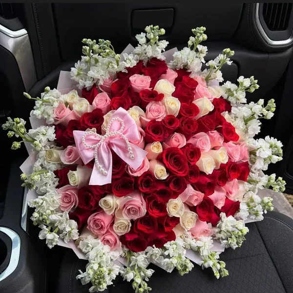 Large bouquet of red, pink, and white roses with a pink bow