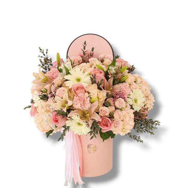 Pink and cream flower arrangement in a round hat box with ribbon