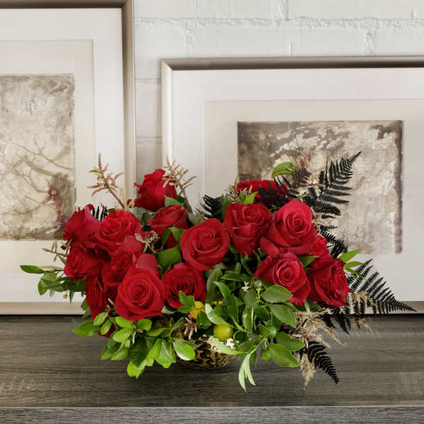 Red roses arranged in a low bowl with greenery