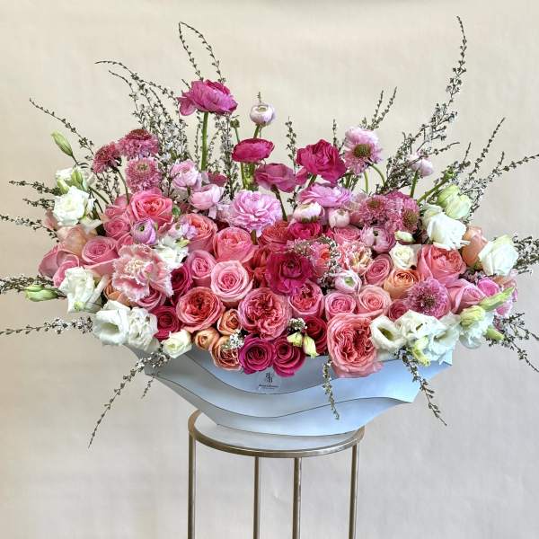 Large pink and white floral arrangement in a white container