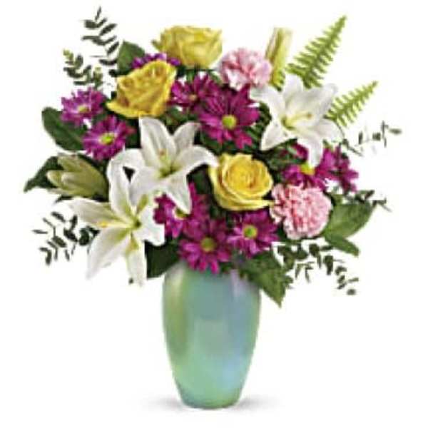 Mixed bouquet of white lilies, yellow roses, and purple daisies in a green vase