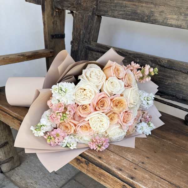 Bouquet of blush, peach, and white roses with small pink and white filler flowers