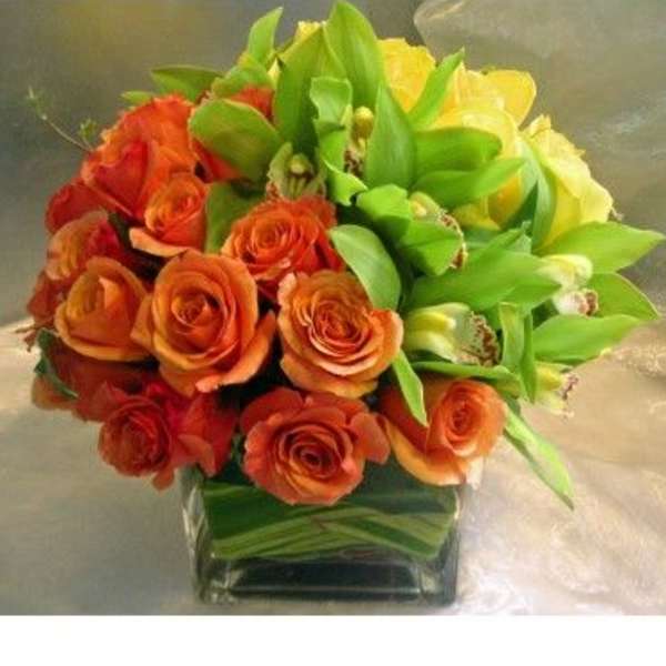 Orange roses and yellow orchids in a square glass vase