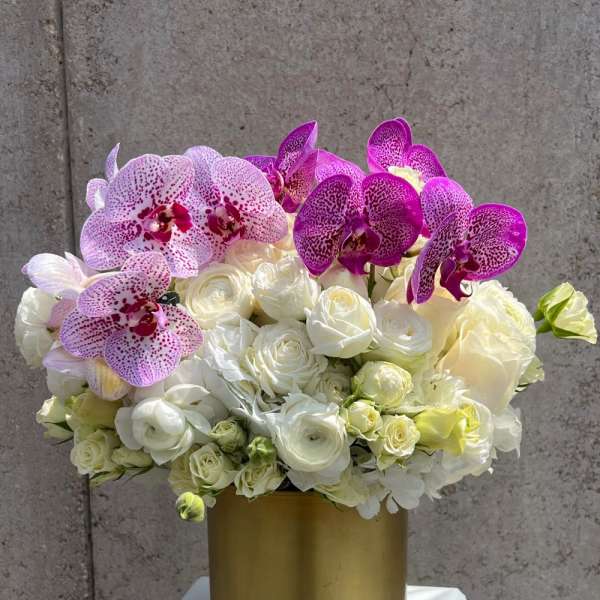 White roses and pink orchids in a gold vase