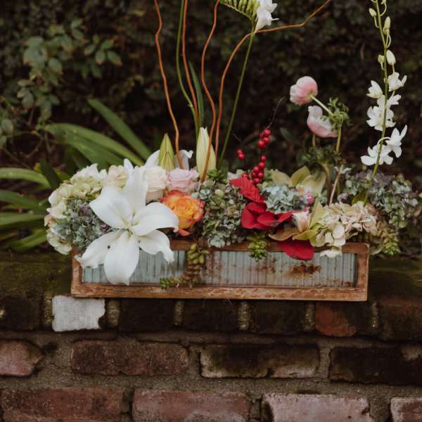 Mixed floral arrangement in a rustic wooden box with tall stems
