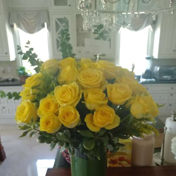 Yellow rose bouquet in a tall green vase