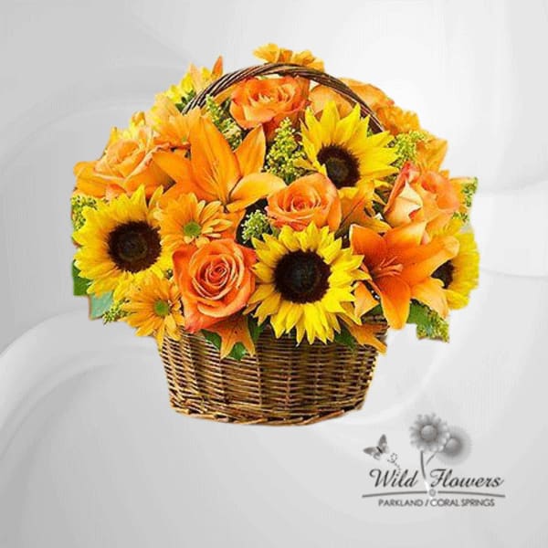 Basket arrangement of orange roses, sunflowers, and lilies