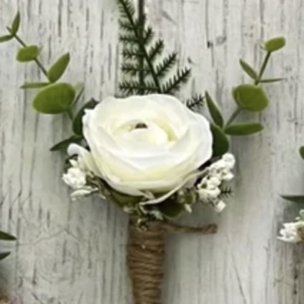White ranunculus boutonniere with greenery and small white accents